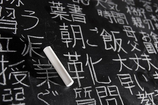 Chalk on blackboard filled with chinese and japanese characters. The words in japanese have random meanings.