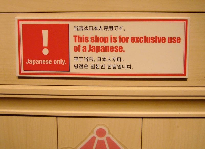 Placa de um estabelecimento escrita em japonês, inglês, chinês e coreano. A placa avisa que a loja é uso de exclusivo de japoneses.