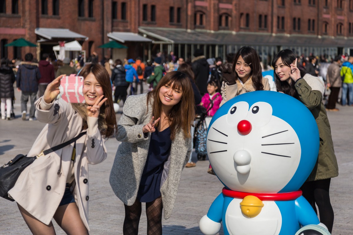 Meninas tiram foto com a figura do Doraemon