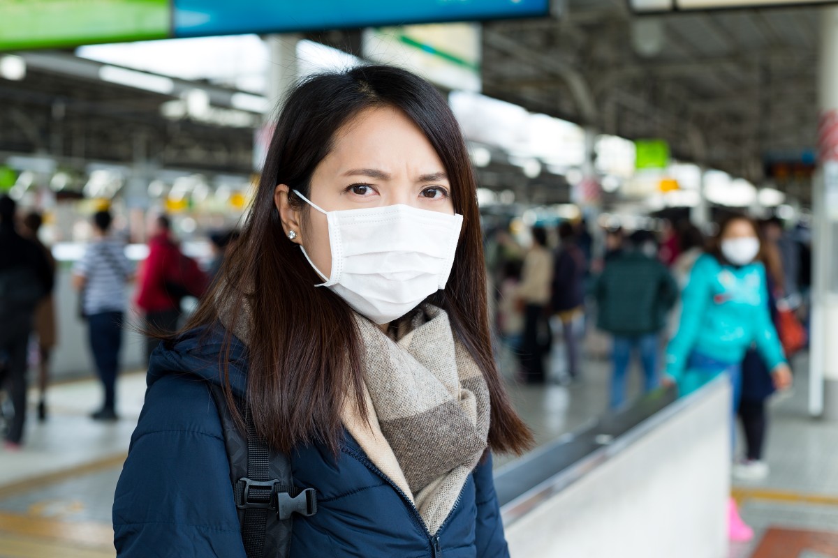 Mujer con mascarilla en la estación de tren