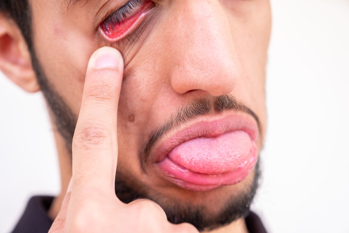 Hombre bajando el párpado y sacando la lengua como símbolo de desaprobación.