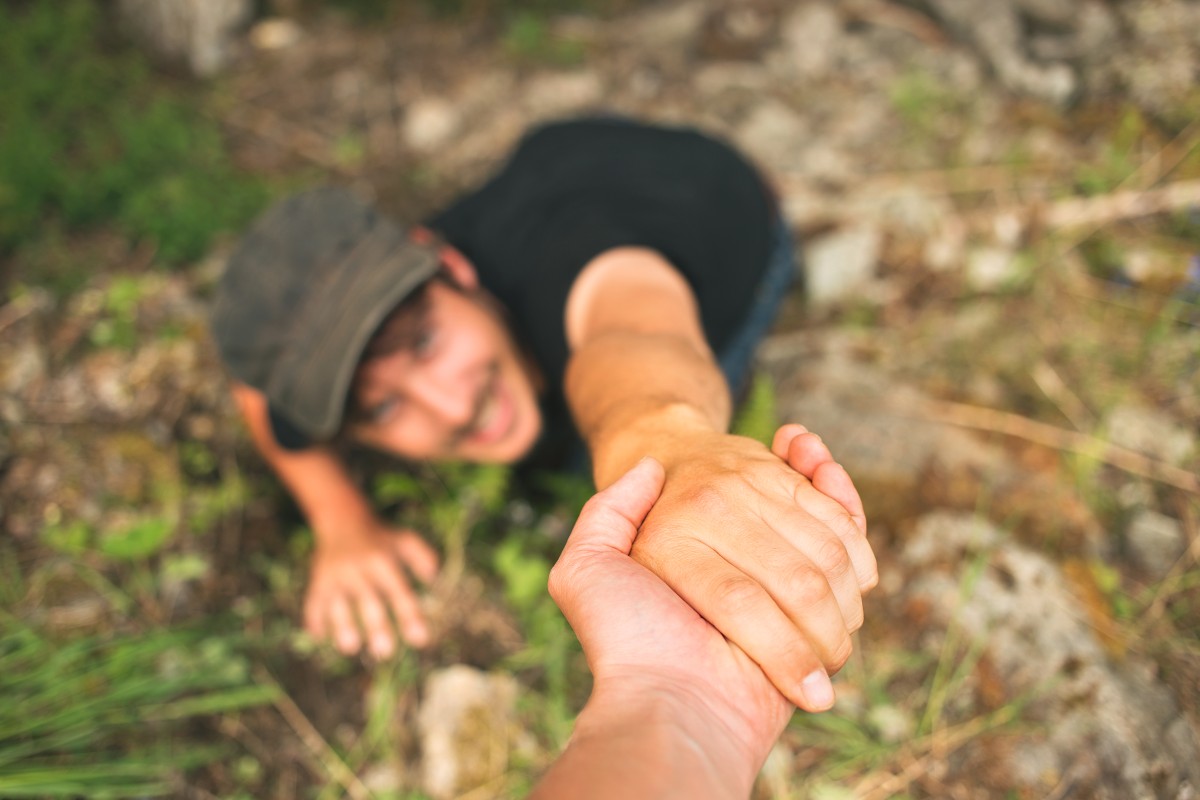 Hand, die einem Mann hilft, sich nach dem Fallen zu heben