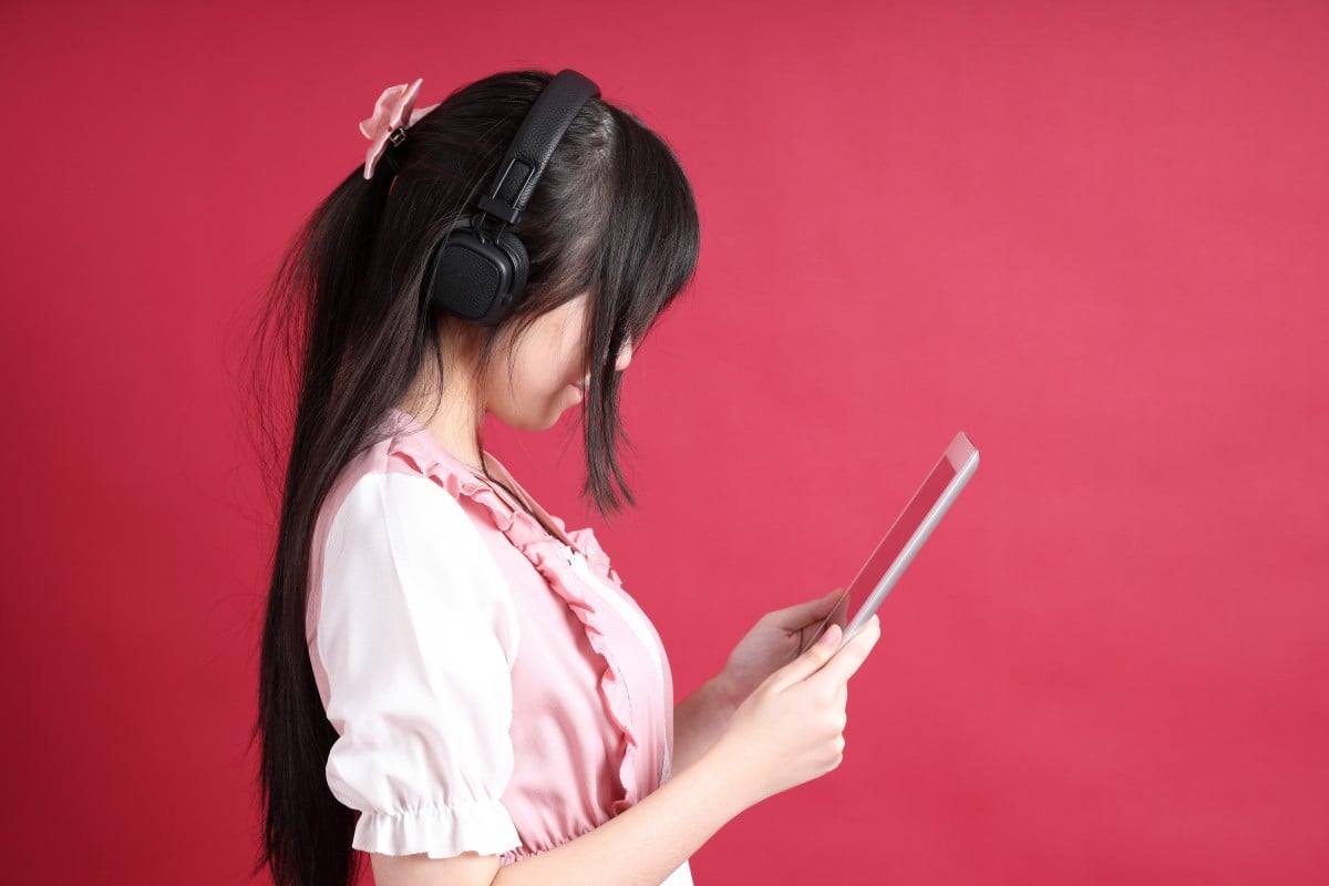 Gadis remaja Asia dengan kostum Jepang lucu berdiri di latar belakang merah.