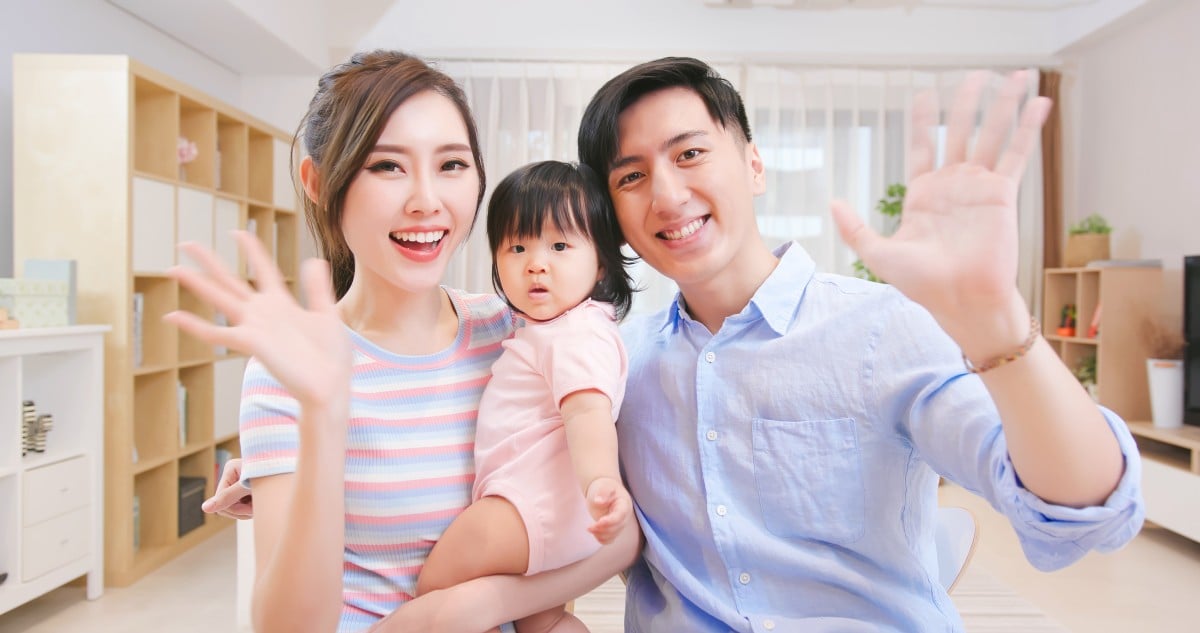 아시아인 젊은 부부와 그들의 딸은 행복하게 웹캠으로 화상 채팅을 합니다.