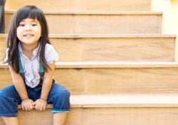 sorriso della ragazza asiatica che si siede sulla linea gialla delle scale
