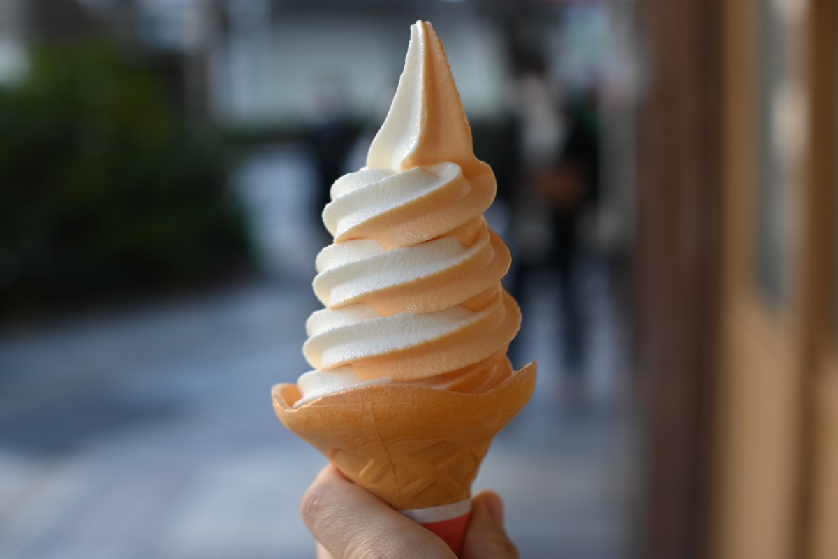 Una mano che tiene un cono gelato su una strada cittadina